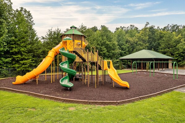 Ein Spielplatz mit Rutschen und einer kleinen Schutzhütte.
