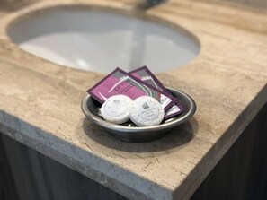 A metal bowl on a countertop with two white circular objects and a purple packet. - Kennedy Dream - Indoor Pool, AC, next to Shopping (Vitacura)