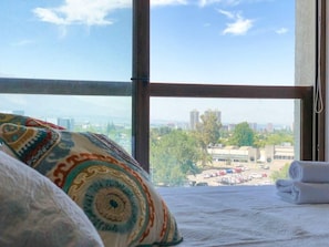 Une chambre d’hôtel dotée d’une grande fenêtre donnant sur la ville.