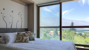 Une chambre avec un grand lit, une vue sur les montagnes et un lac.