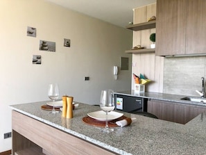 Une cuisine moderne dotée de plans de travail en granit, d’armoires en bois et d’un lave-vaisselle encastré.