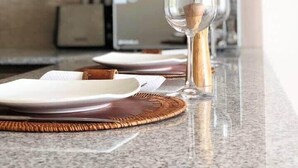 Un comptoir de cuisine aménagé en coin repas, avec des assiettes, un verre doté d’un manche en bois et un set de table en fibres tressées.