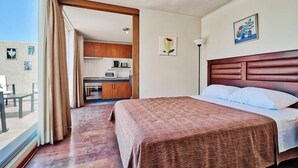 A hotel room with a large bed, a view of the kitchen, and a balcony with curtains. - Bellavista Terrace, BBQ, Parking, AC & City view (Providencia)