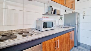 A modern kitchen with stainless steel appliances, wooden cabinets, and a granite countertop. - Bellavista Terrace, BBQ, Parking, AC & City view (Providencia)