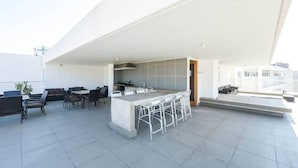 Terraza en la azotea con zona de bar, asientos y cocina.