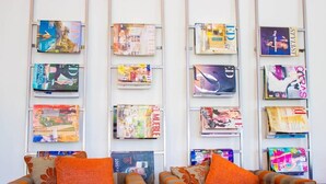 Una habitación con dos sofás y una mesa de centro de cristal, decorada con revistas en la pared.