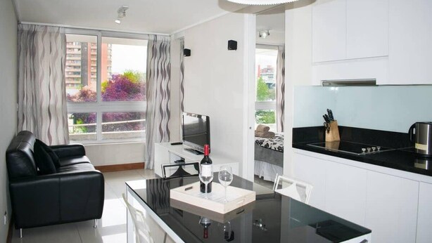 Un apartamento moderno con sala de estar, mesa de comedor y cocina.