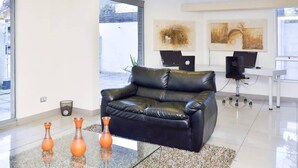 A modern living room with a black leather sofa, two orange vases, and artwork on the wall. - Bellavista Spotlight 1BR Apt - w/Parking & A/C (Providencia)