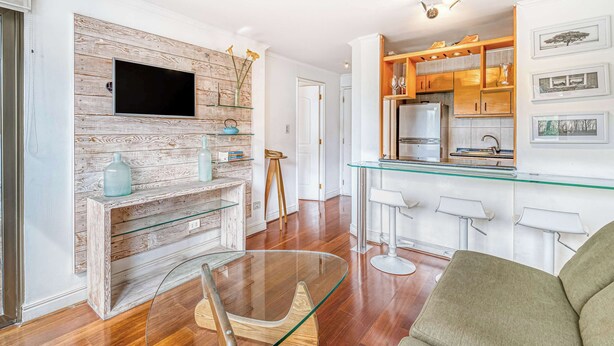 A modern living room with a wooden accent wall, a glass coffee table, and a green sofa.