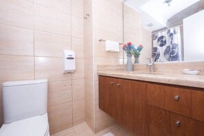 Een moderne badkamer met toilet, wastafel met spiegel en een douchehoek.