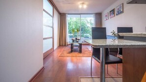 A modern kitchen with a granite countertop, a dining table, and chairs. There is a sliding glass door leading to a balcony with plants. - Bellavista Serenity 1BR - w/Parking, AC & Terrace (Providencia)