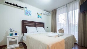 A hotel room with a large bed, a nightstand, a wall-mounted TV, and a window with curtains. - Bellavista Serenity 1BR - w/Parking, AC & Terrace (Providencia)