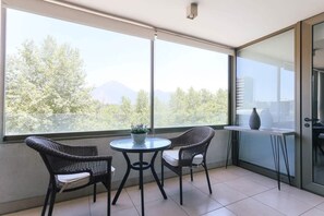A balcony with two wicker chairs, a small round table, and a potted plant.