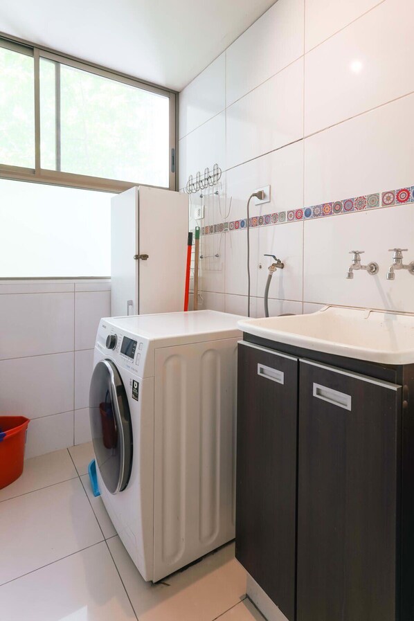 A compact laundry room with a front-loading washer, a sink, and a cabinet.