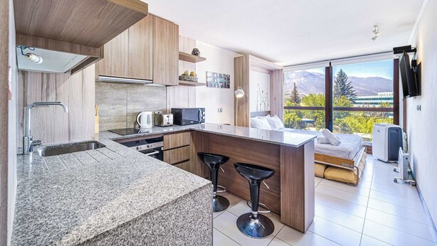 A modern kitchen with granite countertops, wooden cabinets, and a built-in island with bar stools.