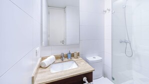 A modern bathroom with a sink, mirror, toilet, and shower.
