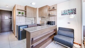 A modern kitchen with wooden cabinetry, a built-in island, and a seating area with a gray sofa.
