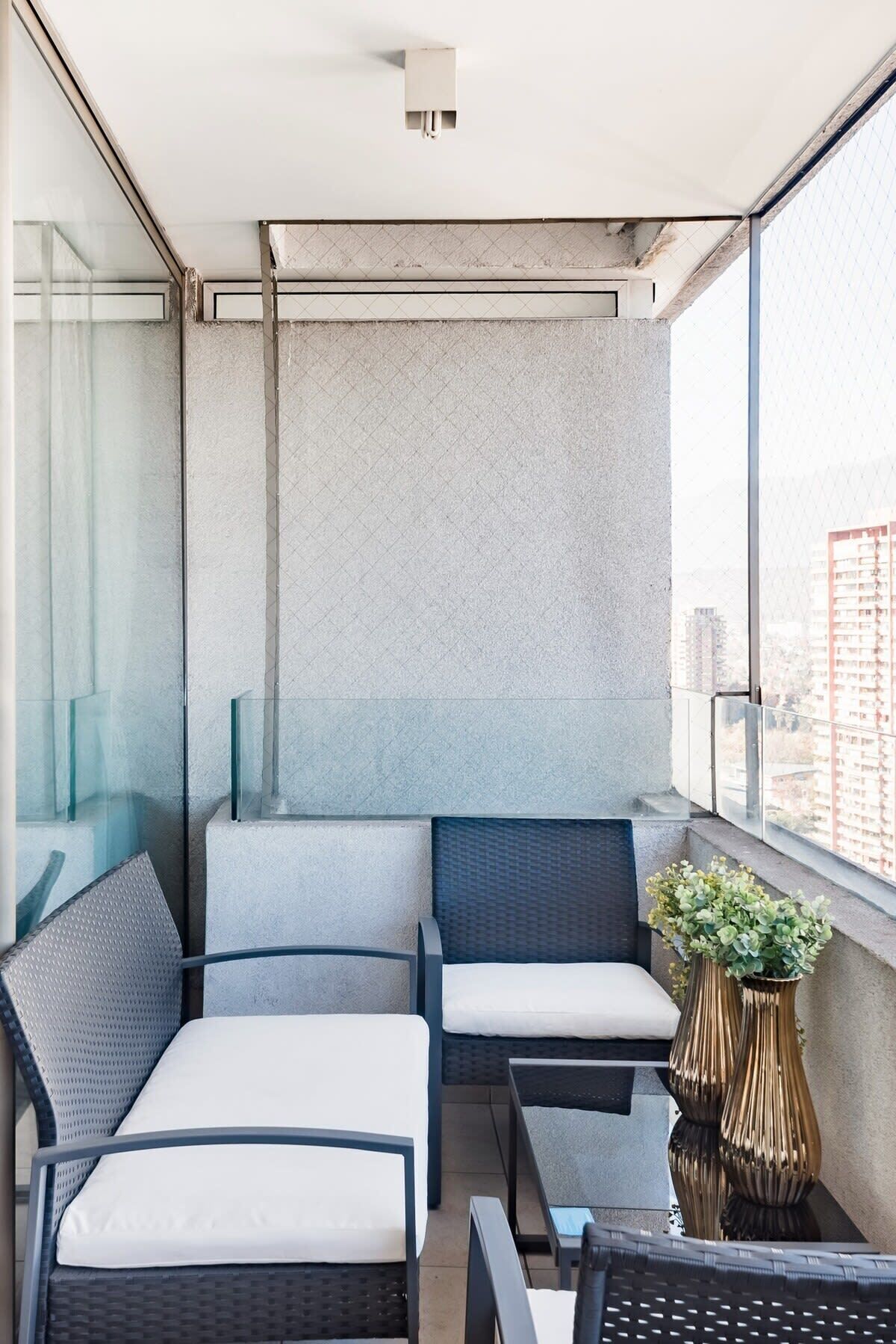 Ein Balkon mit Sitzgelegenheit, einem kleinen Tisch und einer Zierblume.