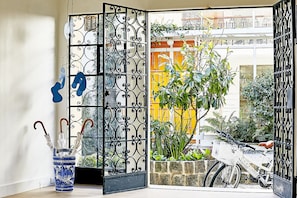 A room with a decorative metal partition, a blue vase with umbrellas, and a bicycle outside. - A Home Away From Home (Comuna Chapinero)