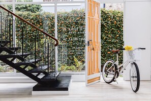 A modern interior with a staircase, a bicycle, and a wall covered in orange flowers. - A Home Away From Home (Comuna Chapinero)