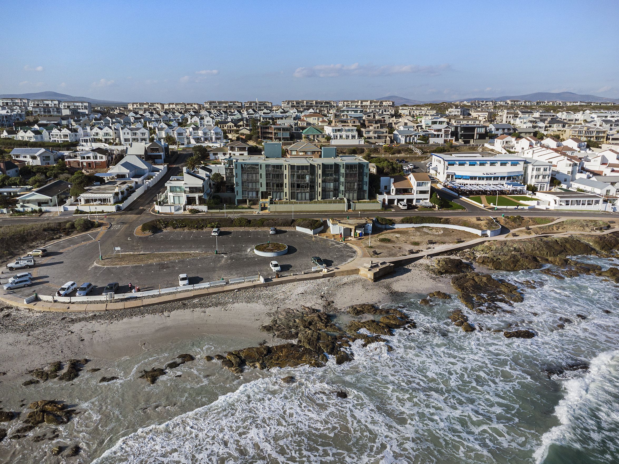 An aerial view of a coastal town with a central building surrounded by residential houses.