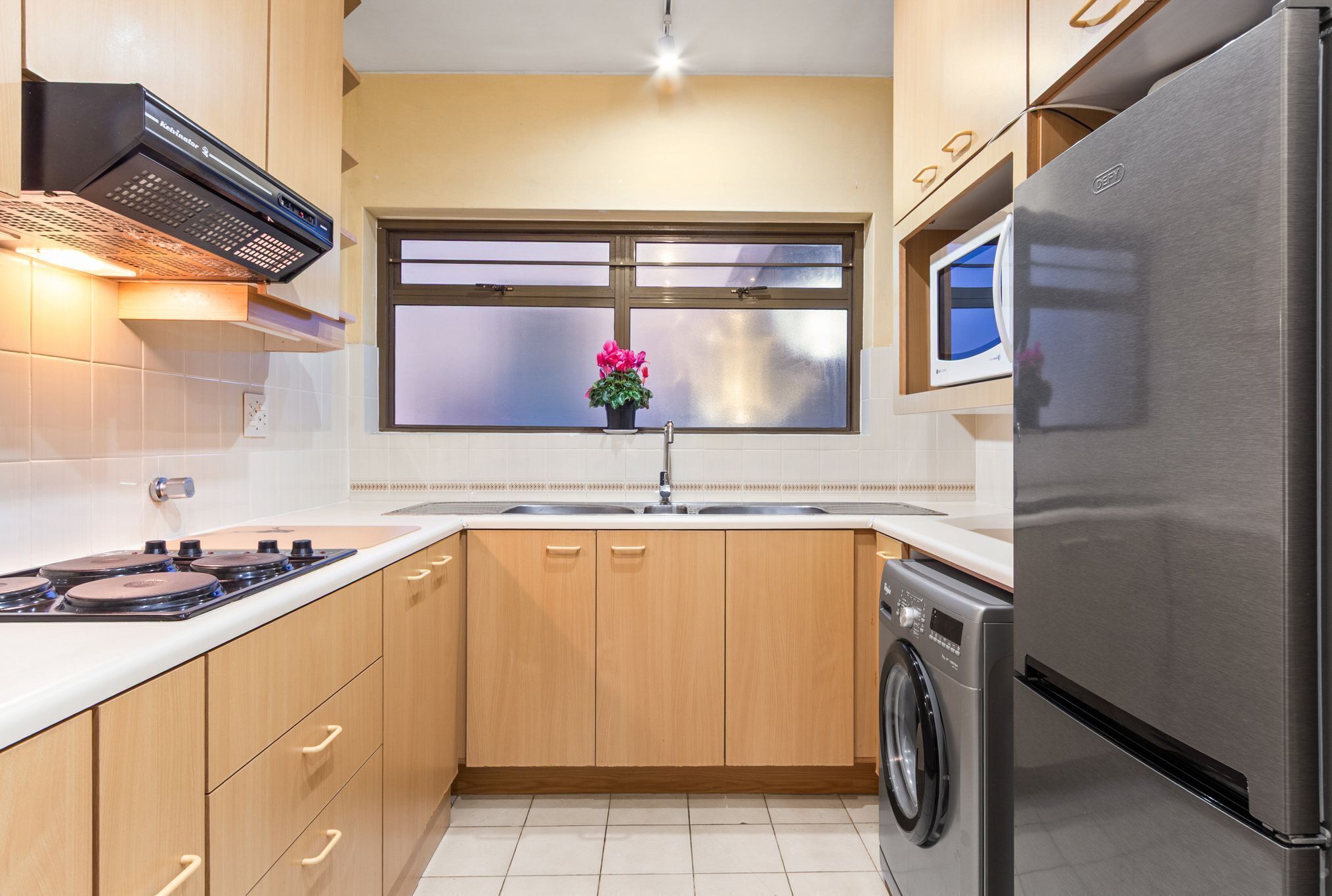 Una cocina moderna con armarios de madera, un refrigerador de acero inoxidable, un horno empotrado y un microondas.