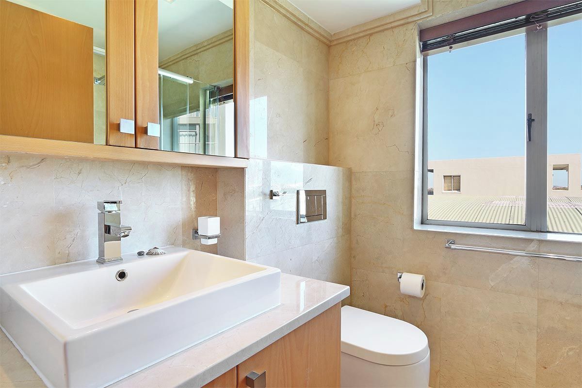 A modern bathroom with a large sink, a toilet, and a window.