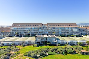 Un hotel moderno con varios pisos, amplias ventanas de vidrio y un jardín bien cuidado.