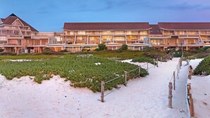 Un hôtel doté de nombreux balcons, d’une plage de sable et d’un jardin bien entretenu.