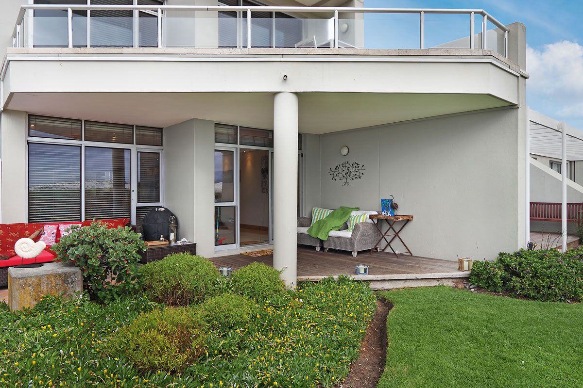 A modern building with a covered patio, outdoor seating, and a garden area.