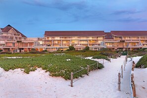A hotel with multiple balconies, a sandy beach area, and a well-maintained garden. - Dolphin Beach E5 (Cape Town)