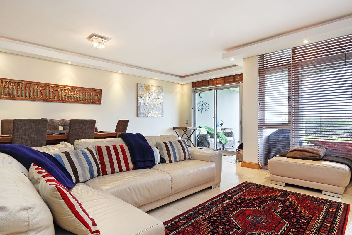 A modern living room with a sectional sofa, a smaller sofa, and a patterned rug.