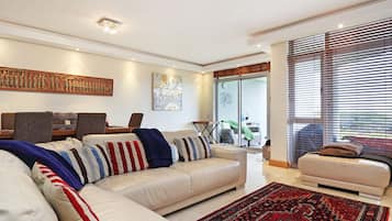 A modern living room with a sectional sofa, a smaller sofa, and a patterned rug.