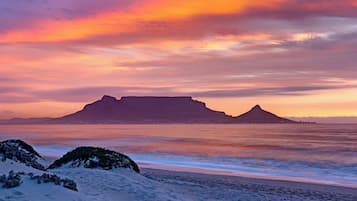 A beach with a mountain in the background and a sunset sky.