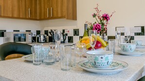 A kitchen with wooden cabinets, a microwave, toaster, and a fruit bowl with flowers on the counter. - Kynsparks Luxury Apartments (Birmingham)