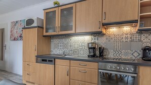 Une cuisine moderne avec des meubles en bois, une cuisinière en acier inoxydable et des carreaux décoratifs sur le mur derrière l’évier.
