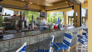 Zona de bar con mostrador, sillas a rayas azules y blancas, y un ventilador de techo.