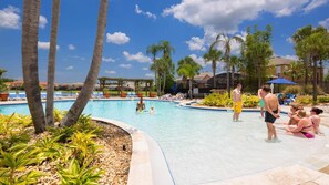A swimming pool area with palm trees, lounge chairs, and a clear blue sky. - Bikini on the Beach by VillaDirect (Kissimmee)