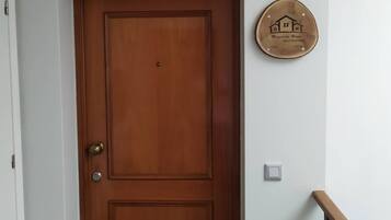 Une porte en bois avec une poignée de porte en laiton, une petite plaque fixée au mur et un escalier avec une rampe en bois.