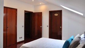Un dormitorio con una cama, puertas de madera y un tragaluz.