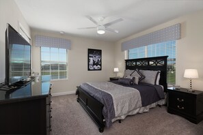 A bedroom with a bed, nightstands, a dresser, a ceiling fan, and patterned window valances. - Fairy Tales by VillaDirect (Kissimmee)