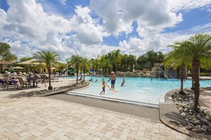 A pool area with a tiled deck, palm trees, and a water feature. - Disneytopia by VillaDirect (Kissimmee)