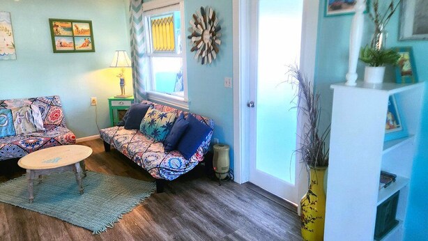 A cozy living room with patterned sofas, a small round table, and a decorative wall piece.