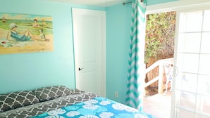 A bedroom with a bed, a door, a window, and a view of the outside.
