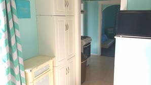 A kitchen with white cabinets, a gas stove, and a trash bin.