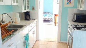 A kitchen with white cabinets, a gas stove, a microwave, and a sink.