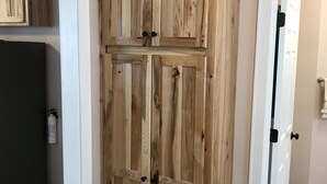 A wooden wardrobe with two doors and a shelf, located in a room with beige walls and tiled flooring. - Twin Maple Cottage, a country cottage get away near Blacksburg - 3BR 1Bath (Dublin)