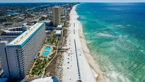 Un paisaje urbano costero con una extensa playa arenosa, un gran hotel de varios pisos y un océano azul claro.