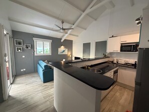 A modern kitchen with a central island, built-in appliances, and a ceiling fan. - Right on the Water | Pool | Le Calme — Althéa (Le Gosier)