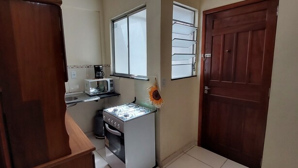 Cocina compacta con estufa a gas, microondas y una pequeña encimera.